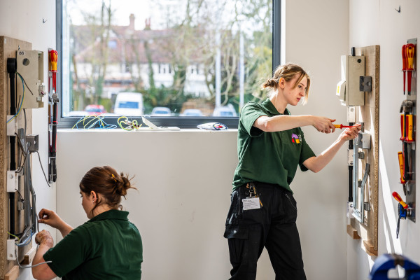 Two electrical students working on wiring in a bay in the new worksop.