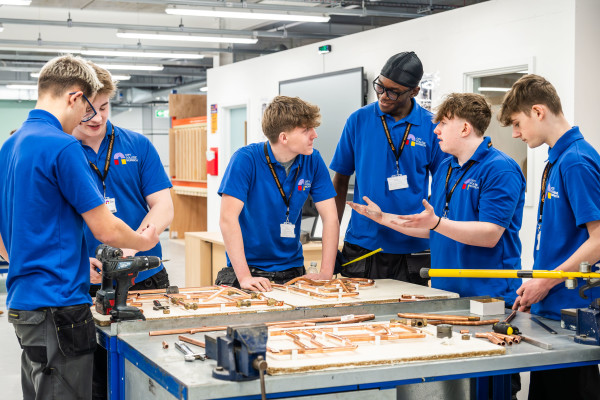 6 plumbing students working with pipes on a workbench in the new building