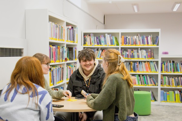 Four students talking at a round table in one of the new seating areas in the library.