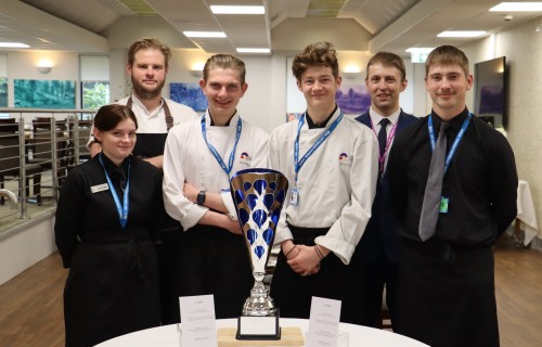 Students in chef whites posing with their trophy