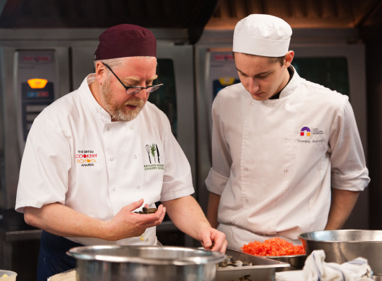 Richard Hughes working with a student in Debut Restaurant kitchens at the city college norwich 125th anniversary dinner